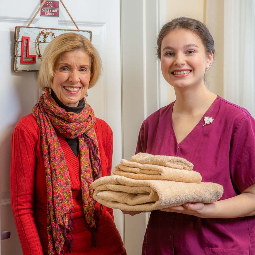 A team member delivering fresh linens to a resident at Ivy Creek